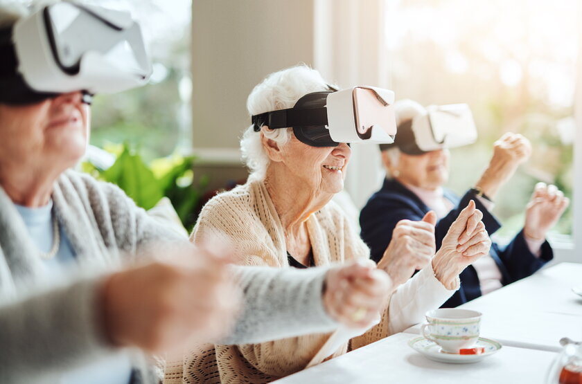 Drei Seniorinnen tragen Virtual Reality Brillen und gestikulieren.