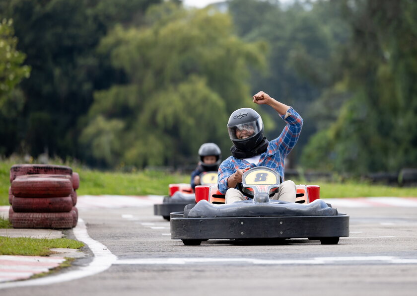 Bild Go Cart Zwei Go Carts verfolgen einander auf Rennbahn ins Ziel, erster Fahrer jubelt.
