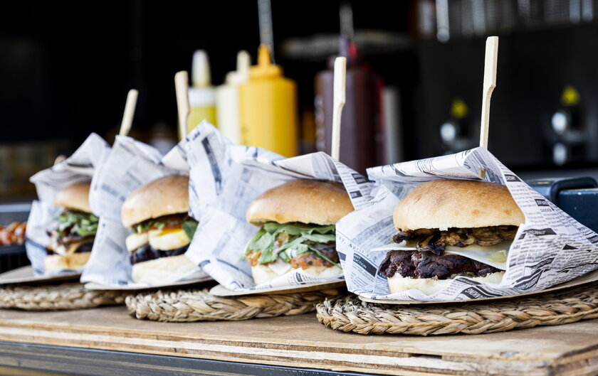 Vier Hamburger nebeneinander am Tresen eines Foodtruck aufgereiht.