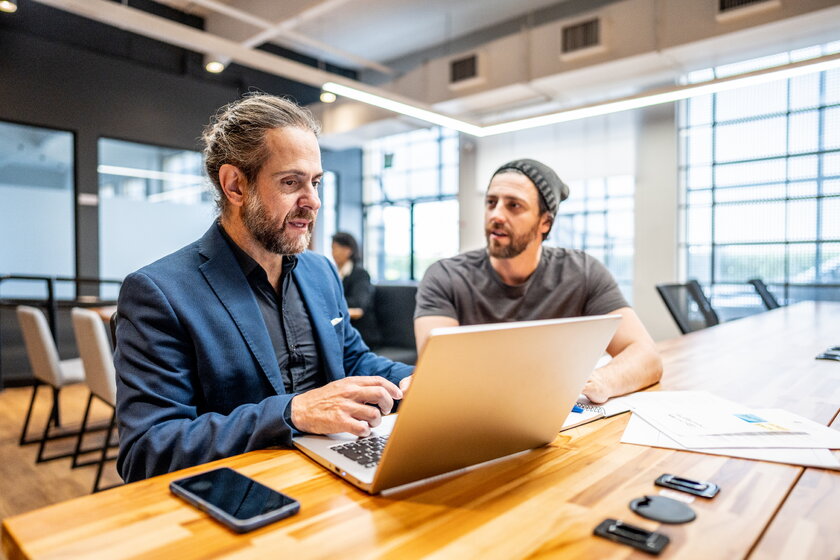 IHK Mitarbeiter und Gruender besprechen gemeinsam Businessplan in modernem Buero.