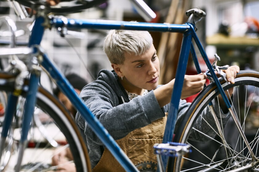 Jungunternehmerin repariert Fahrradbremse in eigener Werkstatt.