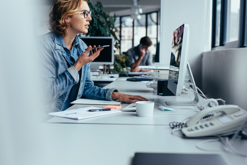 Unternehmerin, die via Freisprecheinrichtung spricht und am Computer arbeitet. 