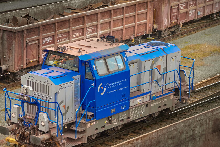 Elektrolokomotive der Verkehrsgesellschaft Peine Salzgitter auf den Gleisen des Stahlwerks, im Hintergrund Waggons mit Metallschrott.