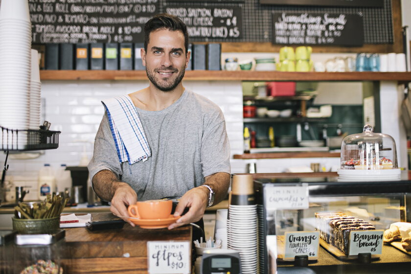 Barista am Tresen bereitet Kaffee fuer Kunden vor.